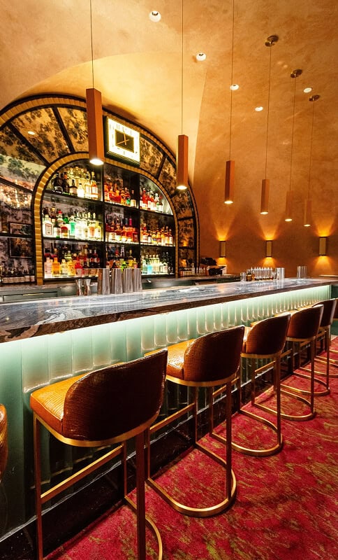 Luxurious bar interior with a well-stocked liquor shelf, modern lighting, and elegant seating, perfect for enjoying crafted cocktails in a sophisticated atmosphere.