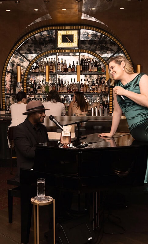 Elegant pianist performing in upscale bar scene with female singer enjoying live jazz, sophisticated atmosphere, and extensive liquor display behind, emphasizing luxury nightlife experience.